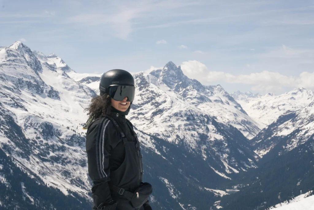 Skier in helmet and goggles looking back at a panorama of Arlberg peaks