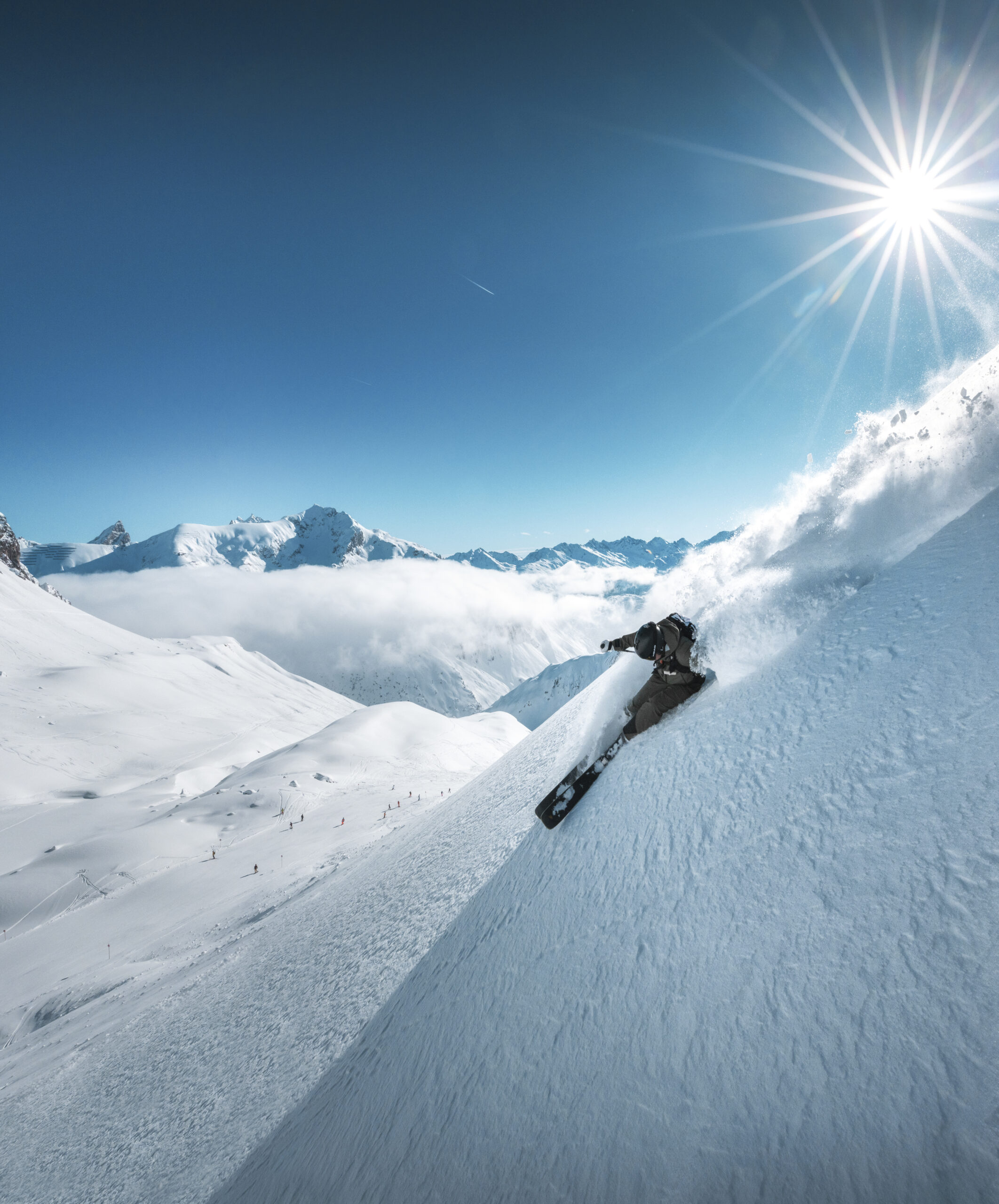 A dynamic shot of a skier slashing through powder on a sunny bluebird day in Zürs