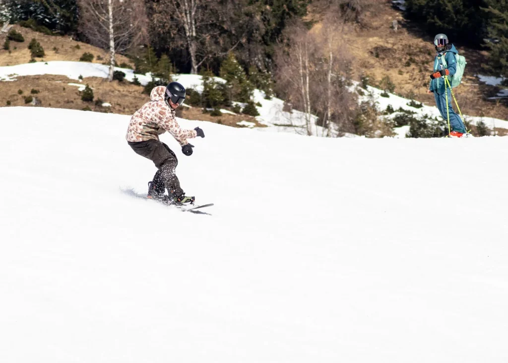 Snowboarder on a wide spring piste in the Arlberg with a second rider behind