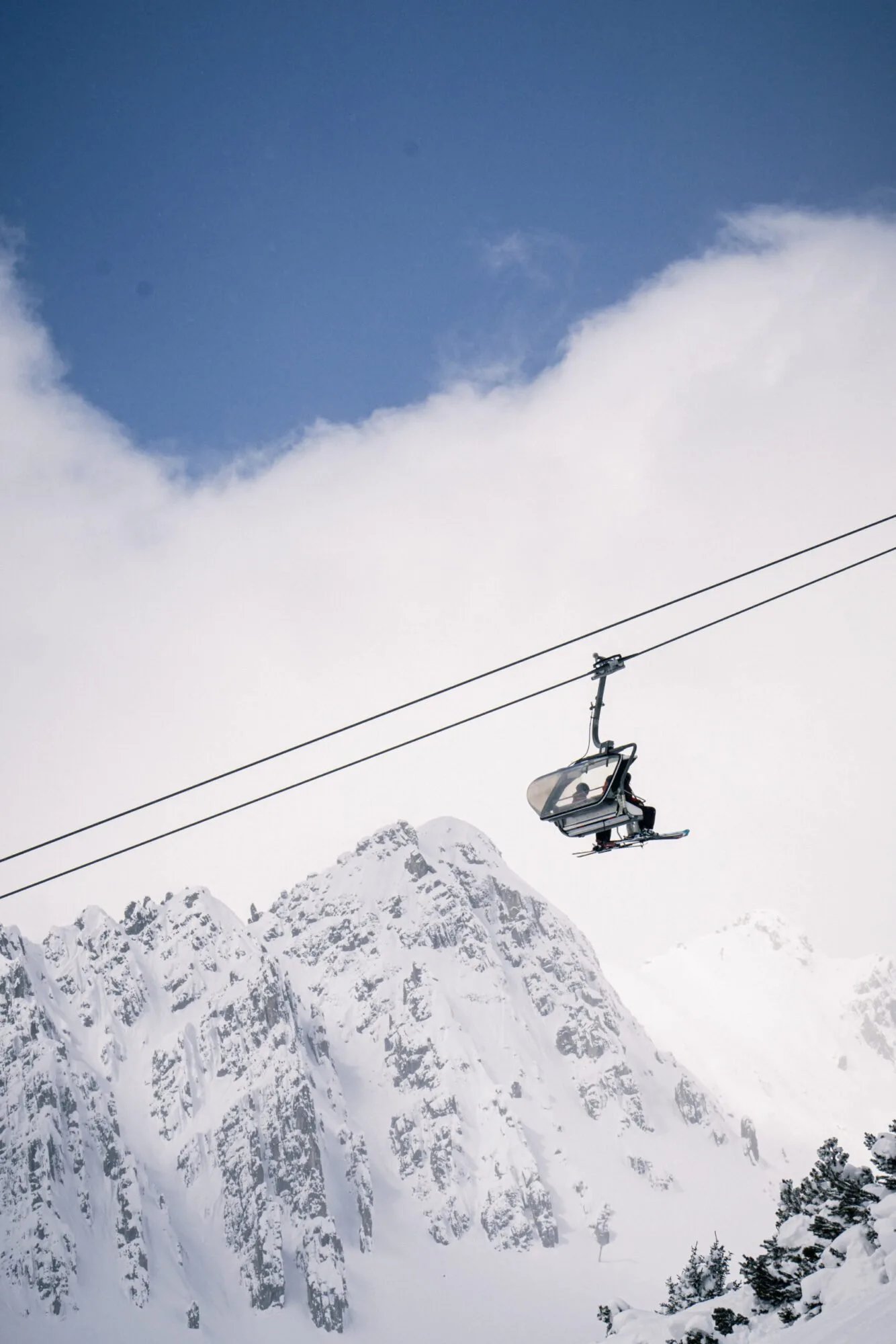 Chairlift rising above snow-covered Arlberg peaks on a bluebird day