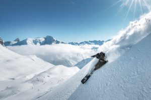 A dynamic shot of a skier slashing through powder on a sunny bluebird day in Zürs