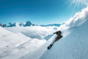 A dynamic shot of a skier slashing through powder on a sunny bluebird day in Zürs
